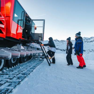 Des touristes montent dans la dameuse sur fond de neige