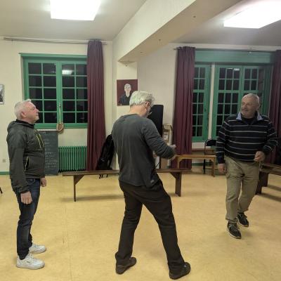 3 danseurs dans une grande salle. On voit la nuit par les fenêtres.