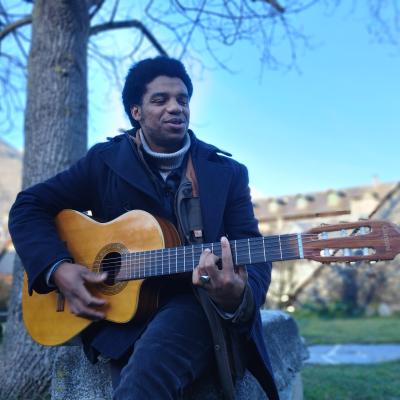 Ozam avec sa guitare dans le parc de la maison de la vallée