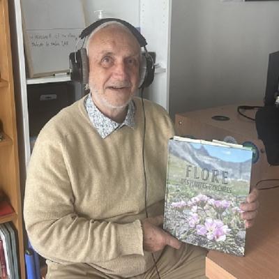 Portrait de l'auteur en pull-over beige avec son livre dans le studio radio et le casque sur les oreilles