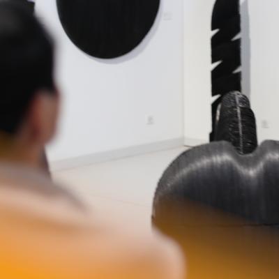 Des sculptures noires dans une pièce blanche et une personne regardant.