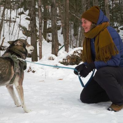 Une femme avec snn chien dans une forêt enneigée.