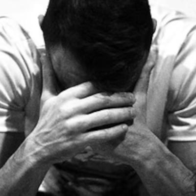 Un homme se tient la tête entre les mains