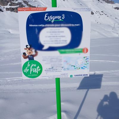 Un panneau avec des questions planté dans la neige avec vue sur les montagnes des pyrénées en arrière-plan