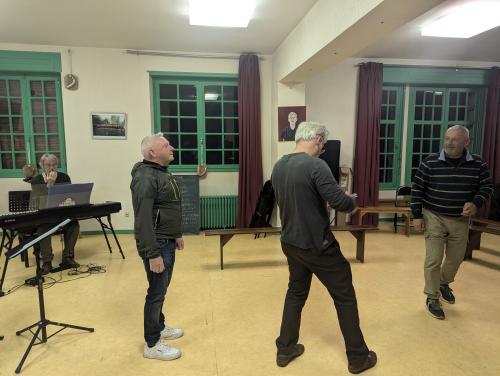 3 danseurs dans une grande salle. On voit la nuit par les fenêtres.