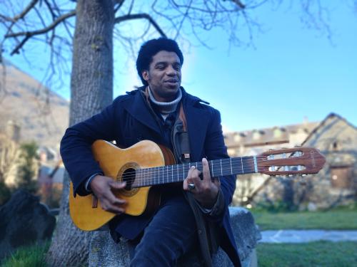 Ozam avec sa guitare dans le parc de la maison de la vallée