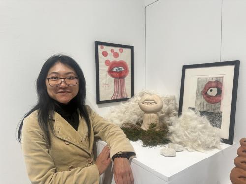 Femme devant des oeuvres d'art (bouche avec des yeux, perruques, mousses végétales