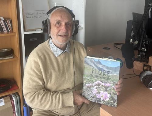 Portrait de l'auteur en pull-over beige avec son livre dans le studio radio et le casque sur les oreilles