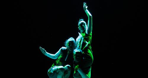 3 danseuses collés les unes aux autres  dans un éclairage vert sur fond noir
