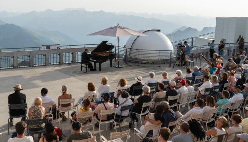 vue d'un concert au pic du midi avec des spectateurs face à un musicien jouant sur un piano à queue.