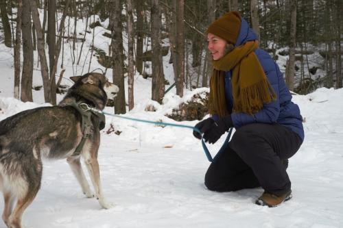 Une femme avec snn chien dans une forêt enneigée.