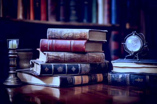 des vieux livres sur une table ancienne avec une bibliothèque en arrière plan